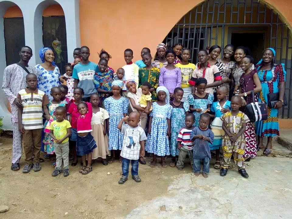 Hands of Hope volunteers standing together with children during an outreach visit